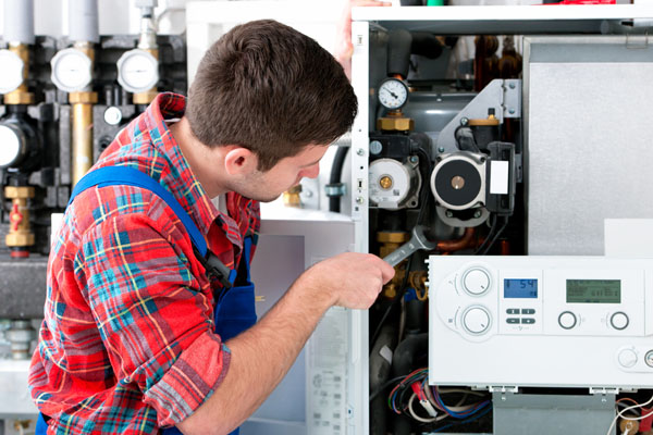 HVAC technician inspecting and repairing boiler controls in Springville