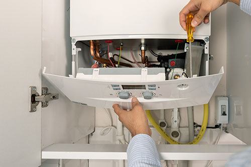 HVAC technician repairing an indoor boiler in Springville