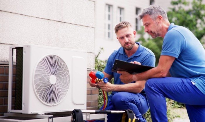 HVAC technicians installing an outdoor air conditioning unit in Springville