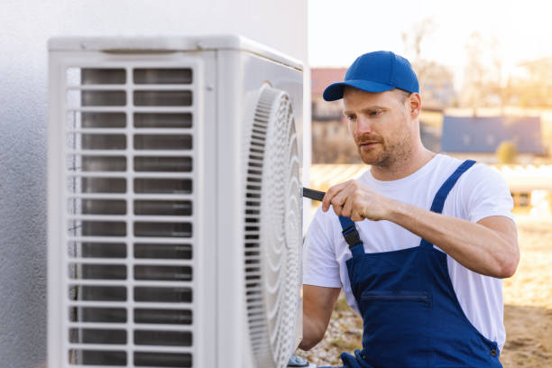 HVAC technician servicing an outdoor air conditioning unit in Springville