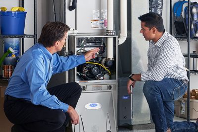 65df8c11f3e4c468cbd351a5_furnace repair vs replacement – Copy HVAC technician explaining furnace repair and maintenance to a homeowner in Springville, UT